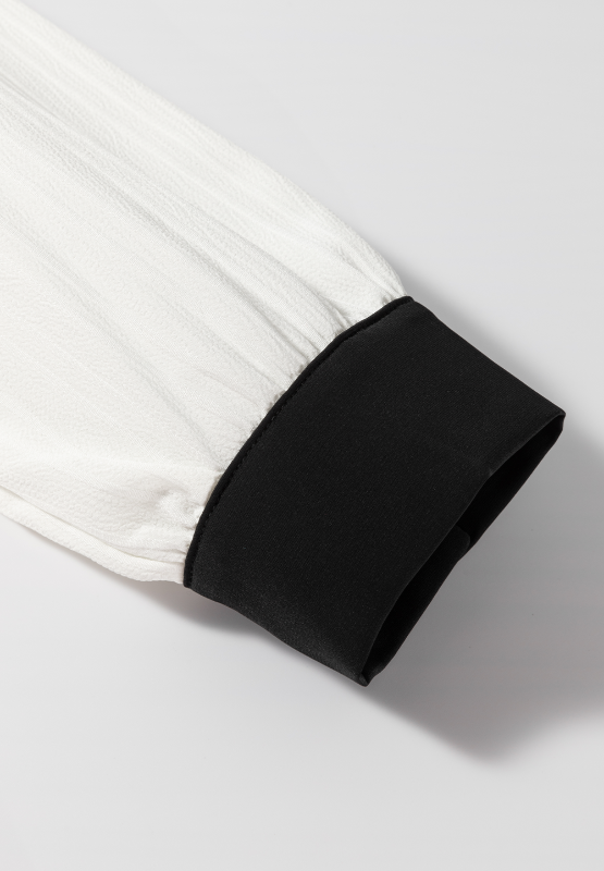 White textured blouse sleeve with black trim detail