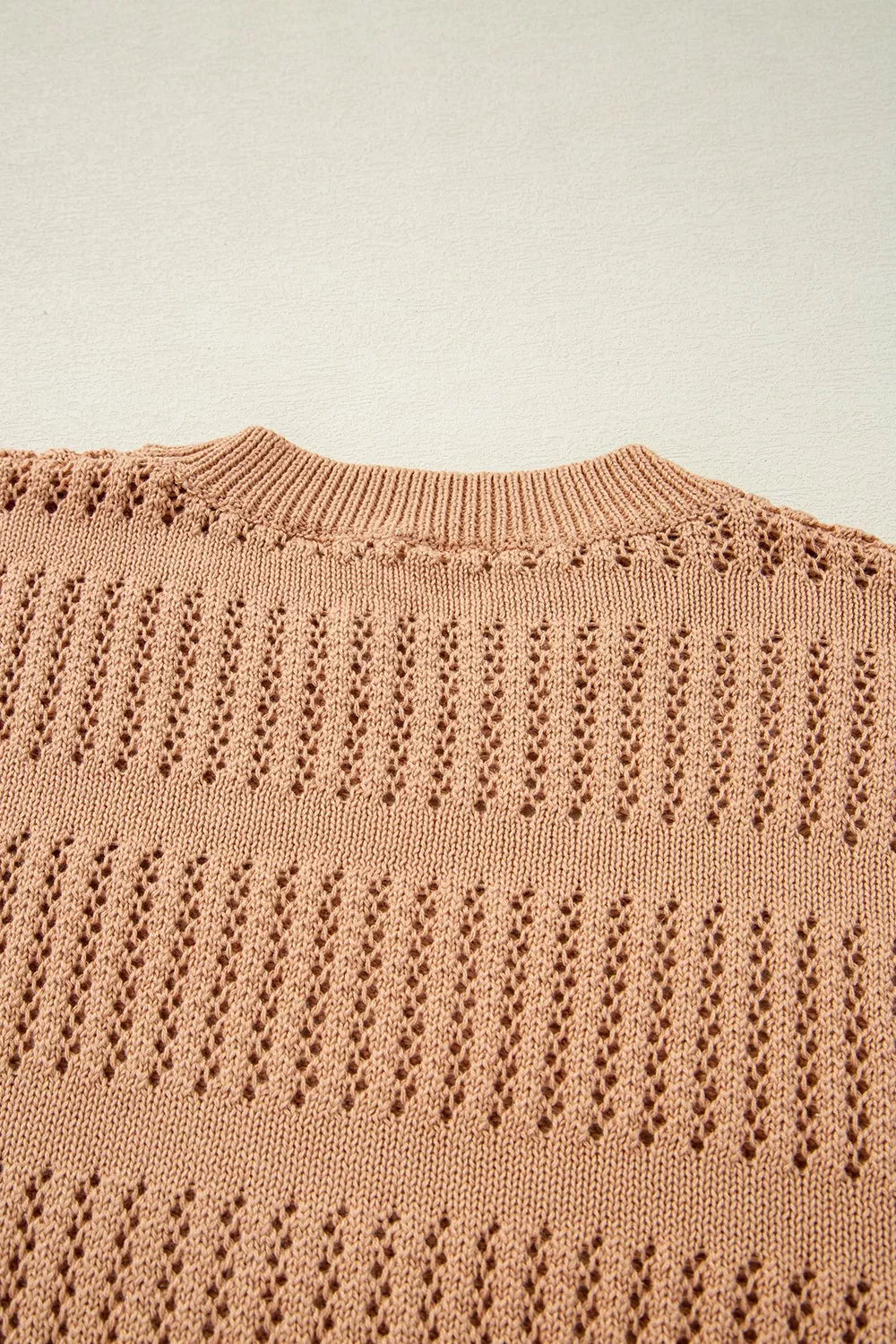 Peach openwork knit sweater with crew neck and elbow sleeves.