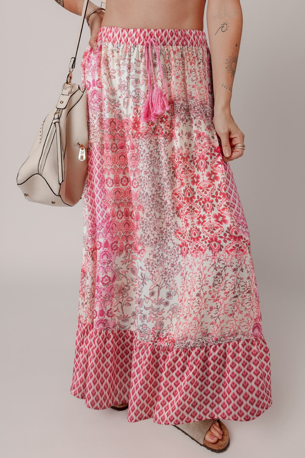 Printed tiered maxi skirt in dusty pink with tassel detail and boho pattern.