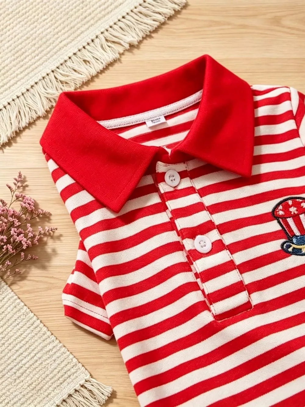 Red and white striped baby polo shirt with patriotic embroidery detail.