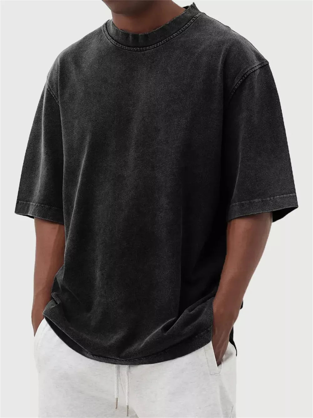 Men's vintage wash oversized black cotton crew neck tee with distressed neckline.