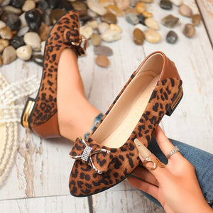 Leopard print pointed-toe block heels with bow detail and gold accents.