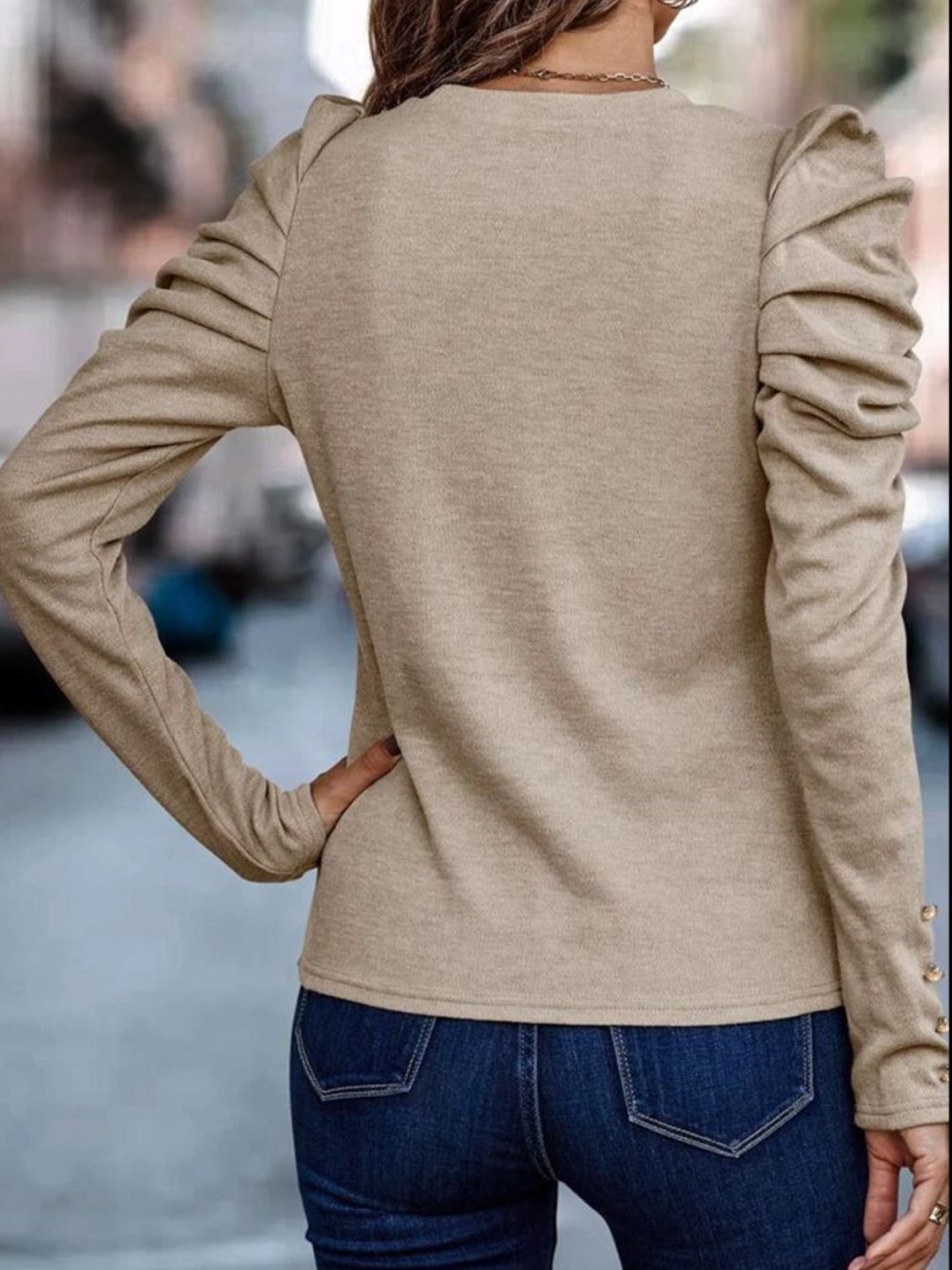Beige knit top with ruched sleeves and gold button detail on cuffs.