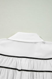 White blouse with black piped trim and ruffled tiers