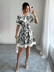 Black floral print mini dress with short sleeves, collar, and tie belt.