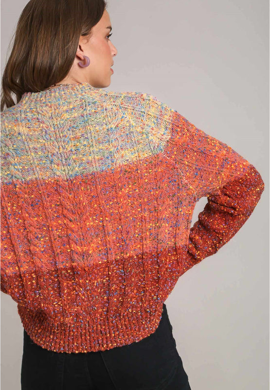 Ombre cable knit crewneck pullover sweater in orange-red with a speckled texture and crew neckline.