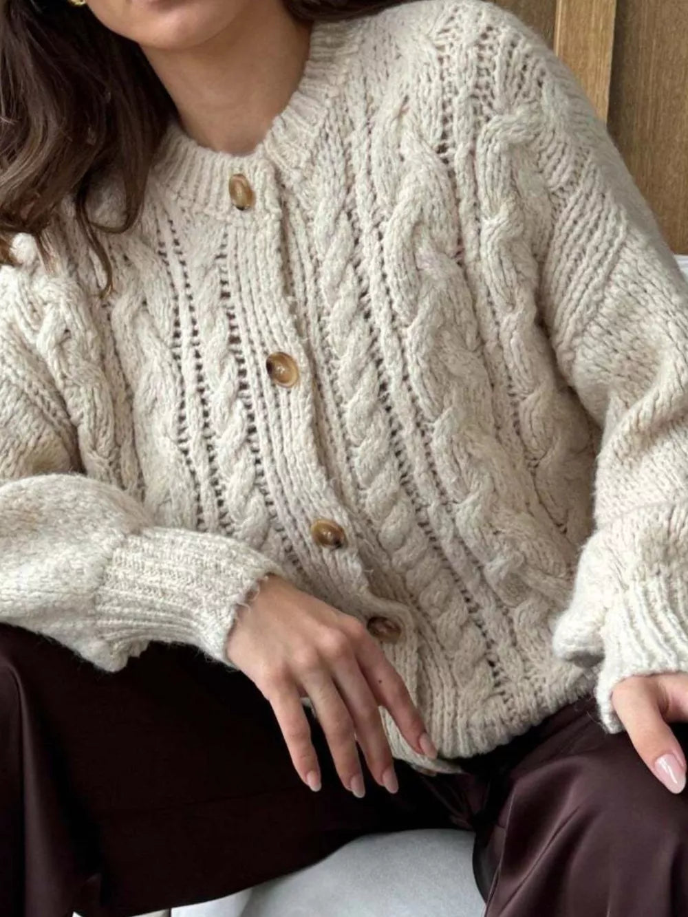 Ivory cable-knit button-down cardigan with textured knit and wooden buttons.