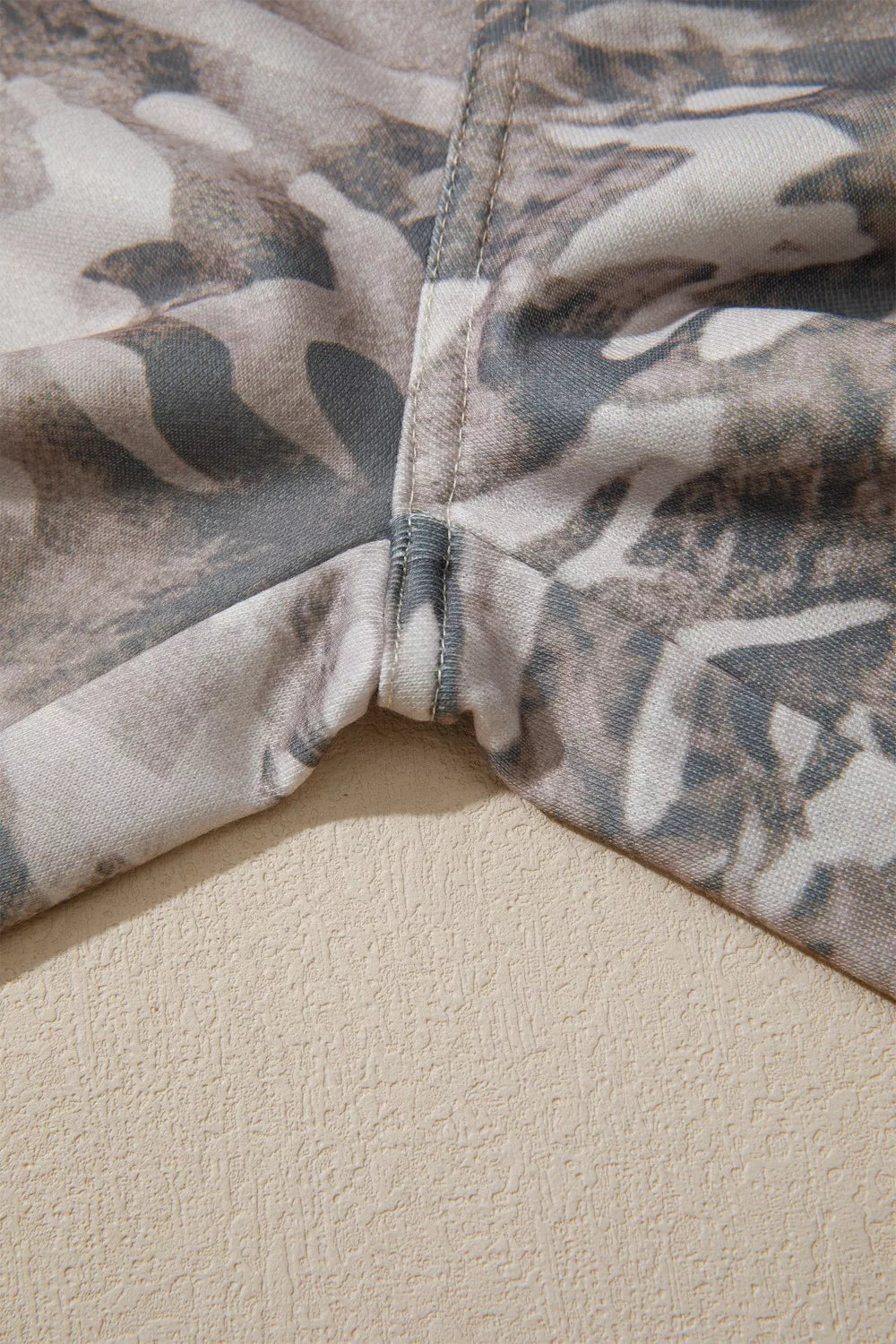 Maternity pants with a grey and beige camo print and reinforced seams.