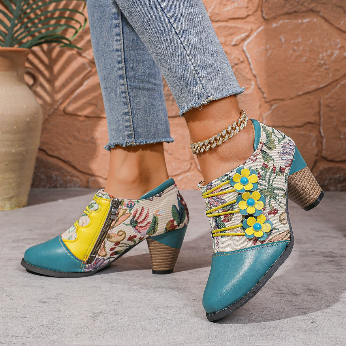 Floral patchwork ankle boots with yellow laces and blue flower details, featuring a side zipper and block heel.