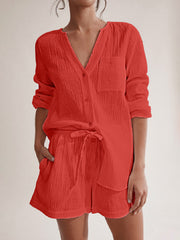 Textured cotton pajama set in orange-red with button-up top and drawstring shorts.