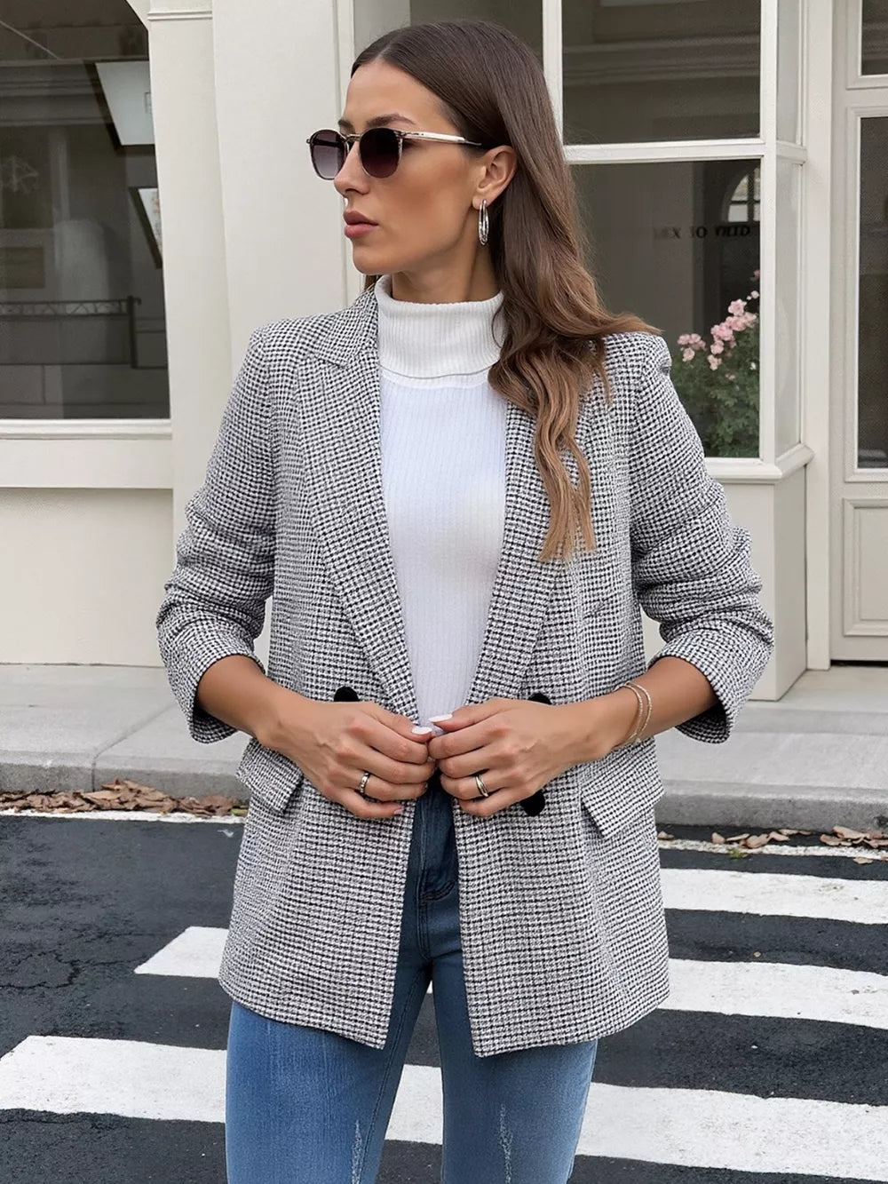 Houndstooth double-breasted blazer with black buttons, worn open over a white turtleneck and blue jeans.