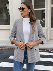 Houndstooth double-breasted blazer with black buttons, worn open over a white turtleneck and blue jeans.