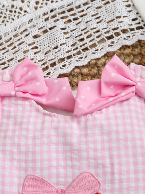 Pink gingham baby one-piece with polka dot bows and baseball embroidery detail.