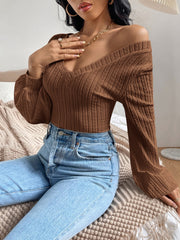 Brown textured chevron blouson top with V-neck and long sleeves styled with jeans.
