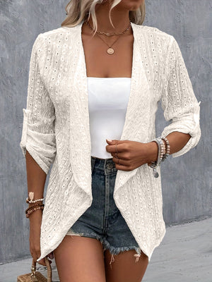 White open-weave draped front cardigan with rolled sleeves, styled with a white tube top and denim shorts.