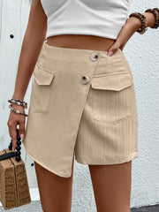 Tan high-waist tailored shorts with asymmetric wrap front and button closure.