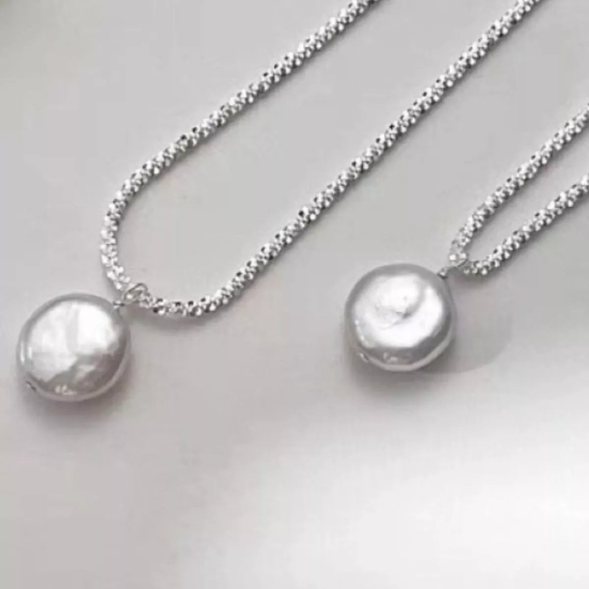 Silver pearl pendant necklace with a textured chain.