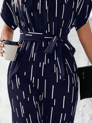 Dark blue wide-leg jumpsuit with white raindrop print, belted waist, and short sleeves.