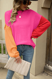 Colorblock knit pullover sweater with hot pink, red, and orange sleeves.