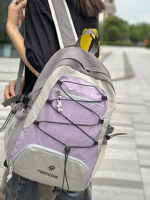 Earthy toned lightweight nylon backpack in purple and beige with bungee cord detail and mesh pockets.