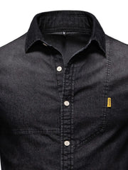 Dark wash denim shirt with asymmetric pocket detail and button-down front.