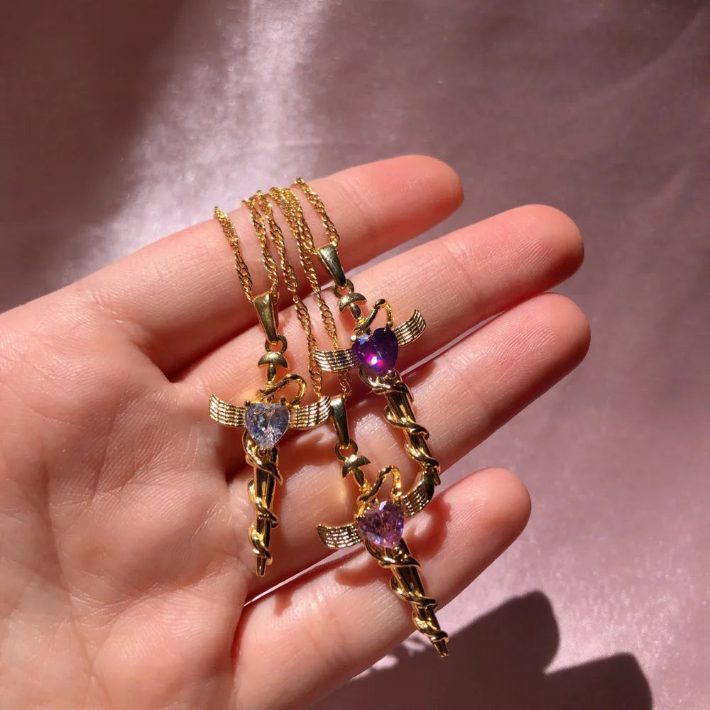 Heart-shaped cross charm pendant necklaces with wings, 18K gold-plated, in purple and light purple.