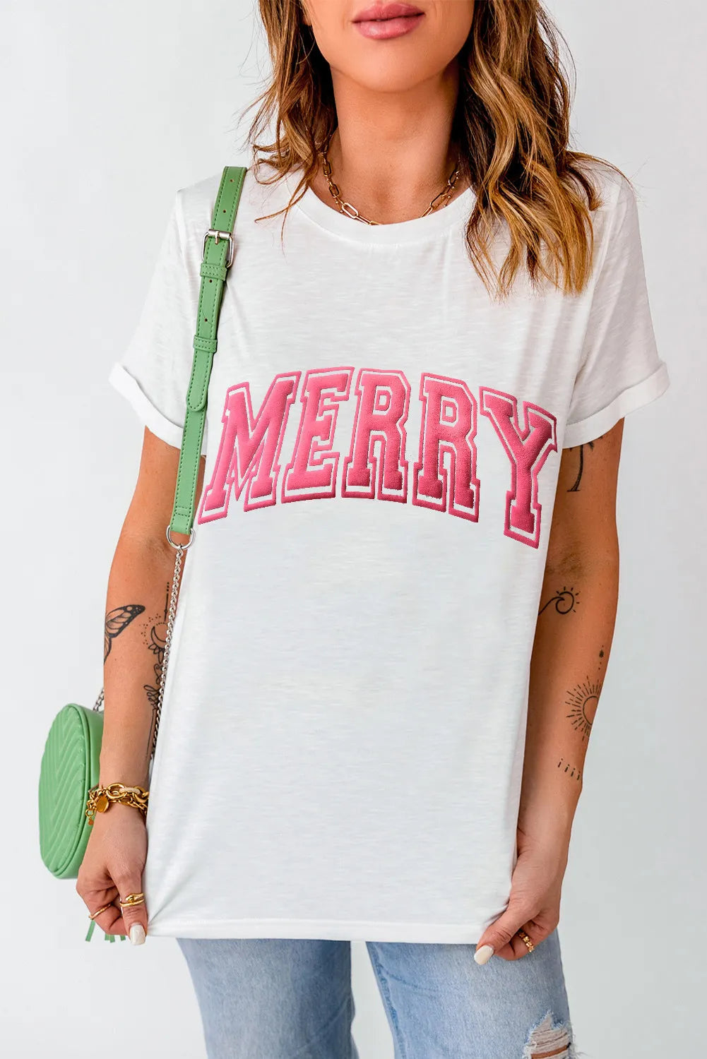 White t-shirt with pink varsity "MERRY" embroidery and cuffed sleeves.
