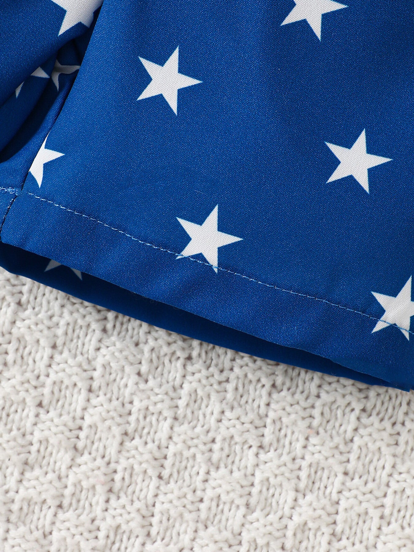 Blue cotton baby shorts with white stars and elastic waistband detail.