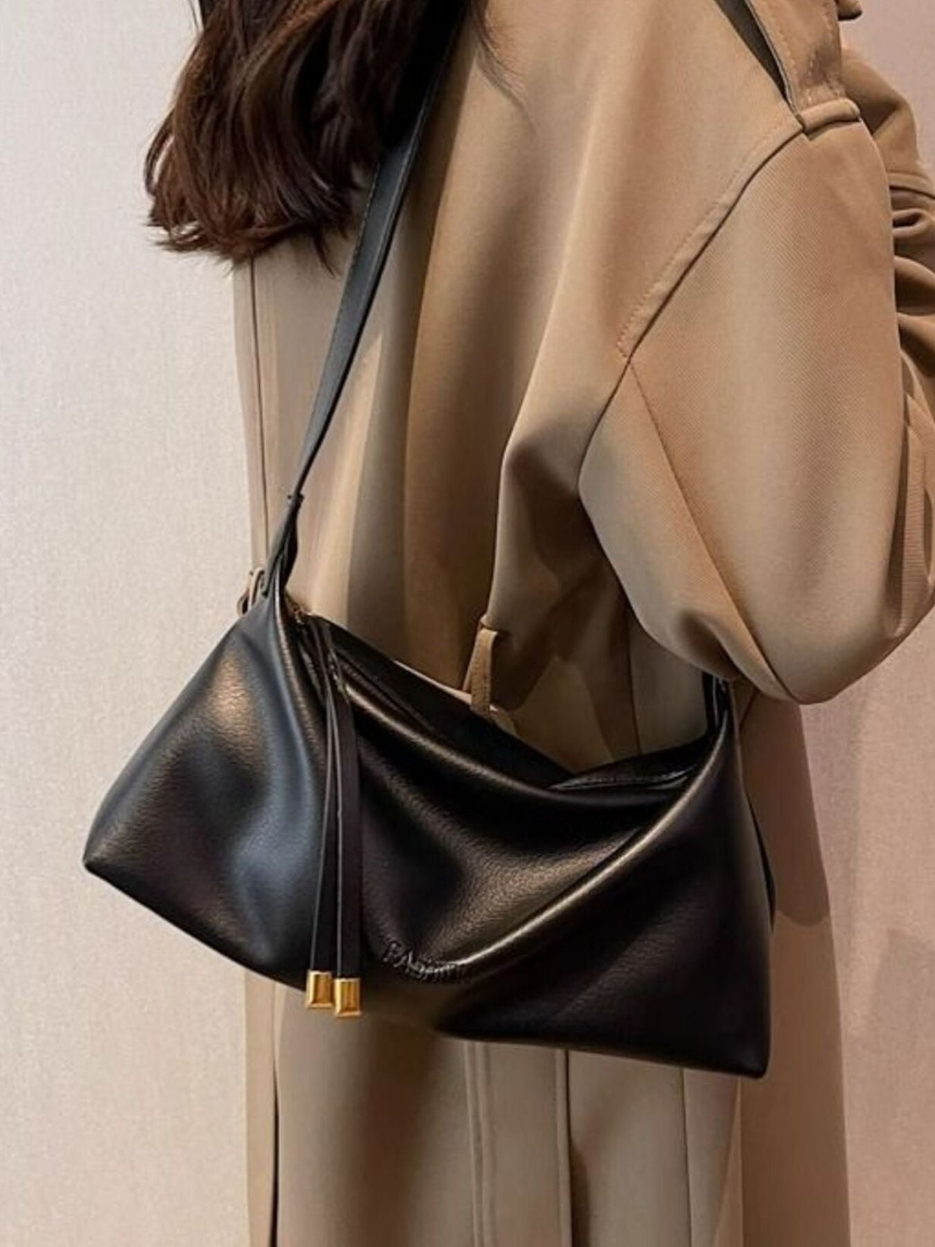 Black slouchy crossbody bag with adjustable strap and gold hardware details.
