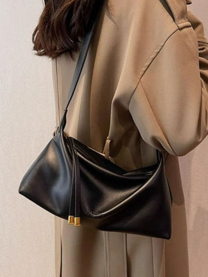 Black slouchy crossbody bag with adjustable strap and gold hardware details.
