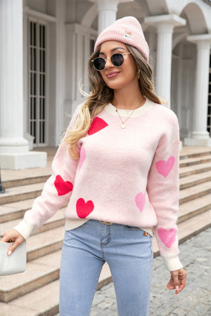Blush pink intarsia knit crewneck sweater with red and pink hearts, cream neckline and cuffs.