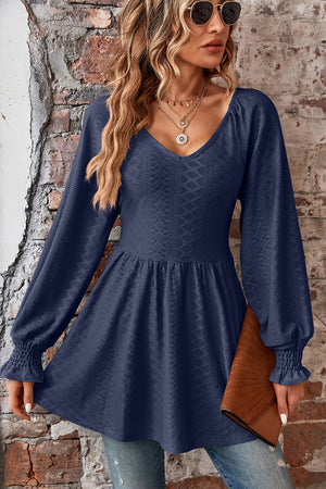 Dark blue textured blouse with V-neck, empire waist, and shirred bell sleeves.