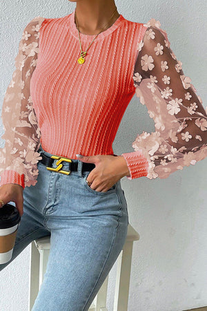 Coral knit top with sheer floral appliqué sleeves and crew neck.