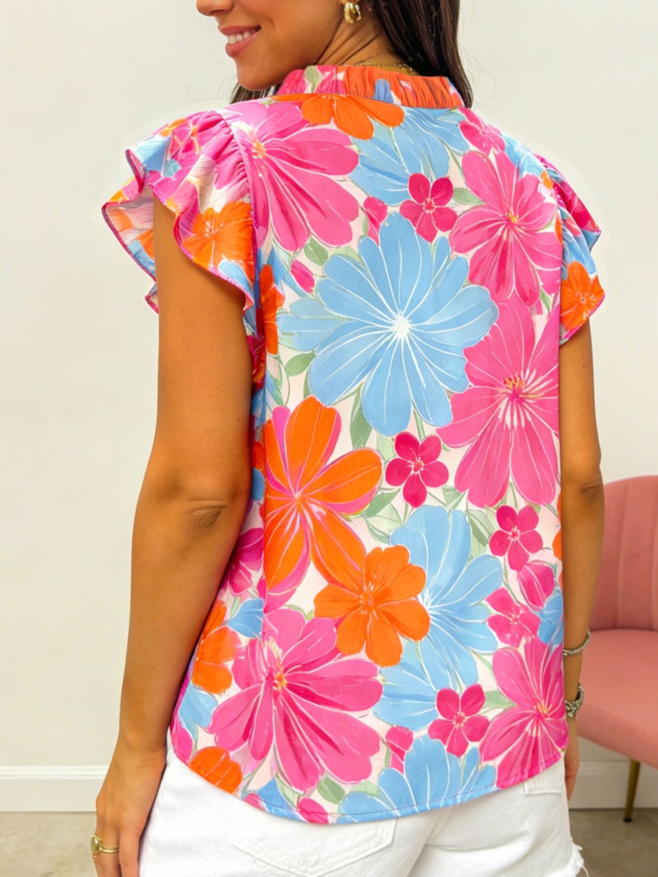 Tie neck ruffle blouse with bright floral print in pink, blue, and orange.