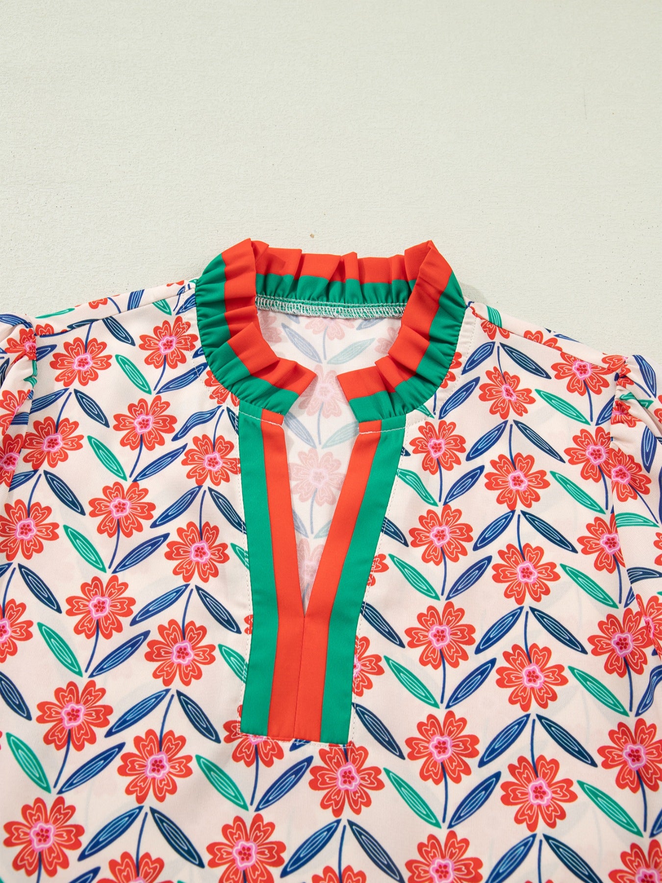 Floral ruffled v-neck shirt with striped trim and colorful floral pattern