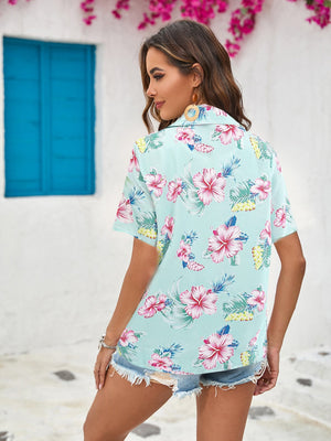 Tropical print camp collar shirt in sky blue with hibiscus flowers, short sleeves, and button front.