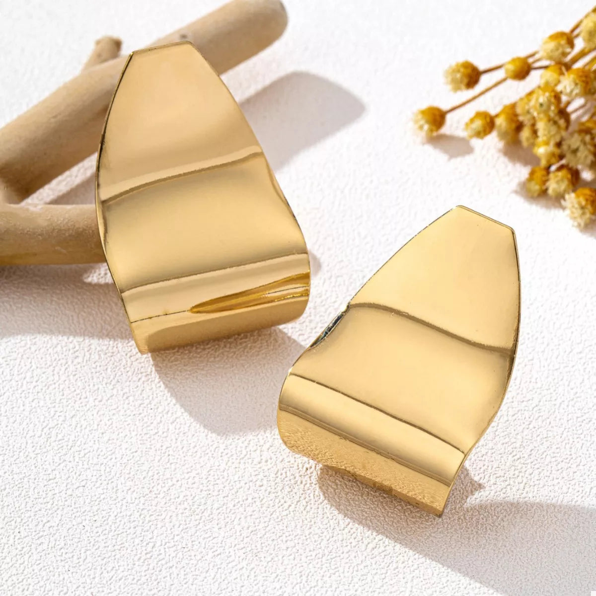 Golden alloy geometric earrings with a polished finish and abstract shape.
