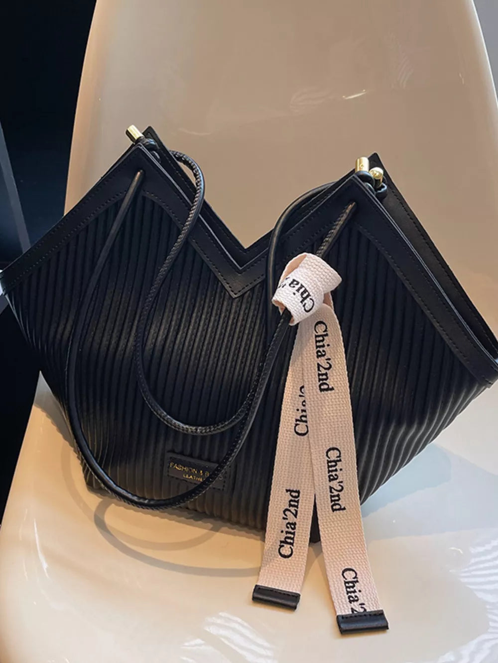 Black ribbed texture large shoulder bag with decorative ribbon detail.
