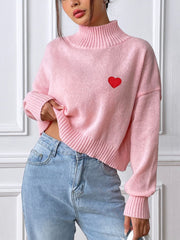 Blush pink cropped turtleneck knit sweater with embroidered red heart detail.
