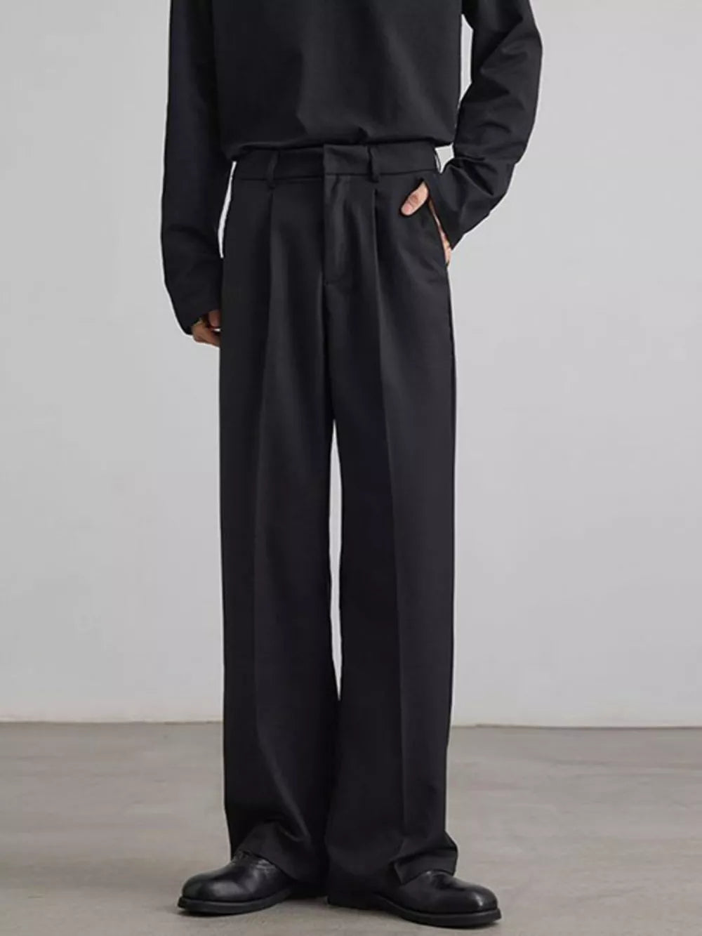 Black pleated wide-leg trousers with a relaxed fit and side pockets.