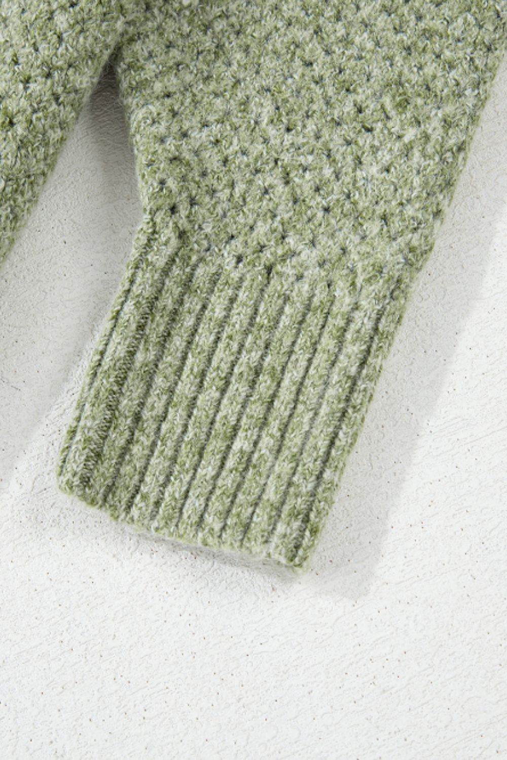 Matcha green open-knit slouchy V-neck sweater with ribbed cuffs and textured knit detail.