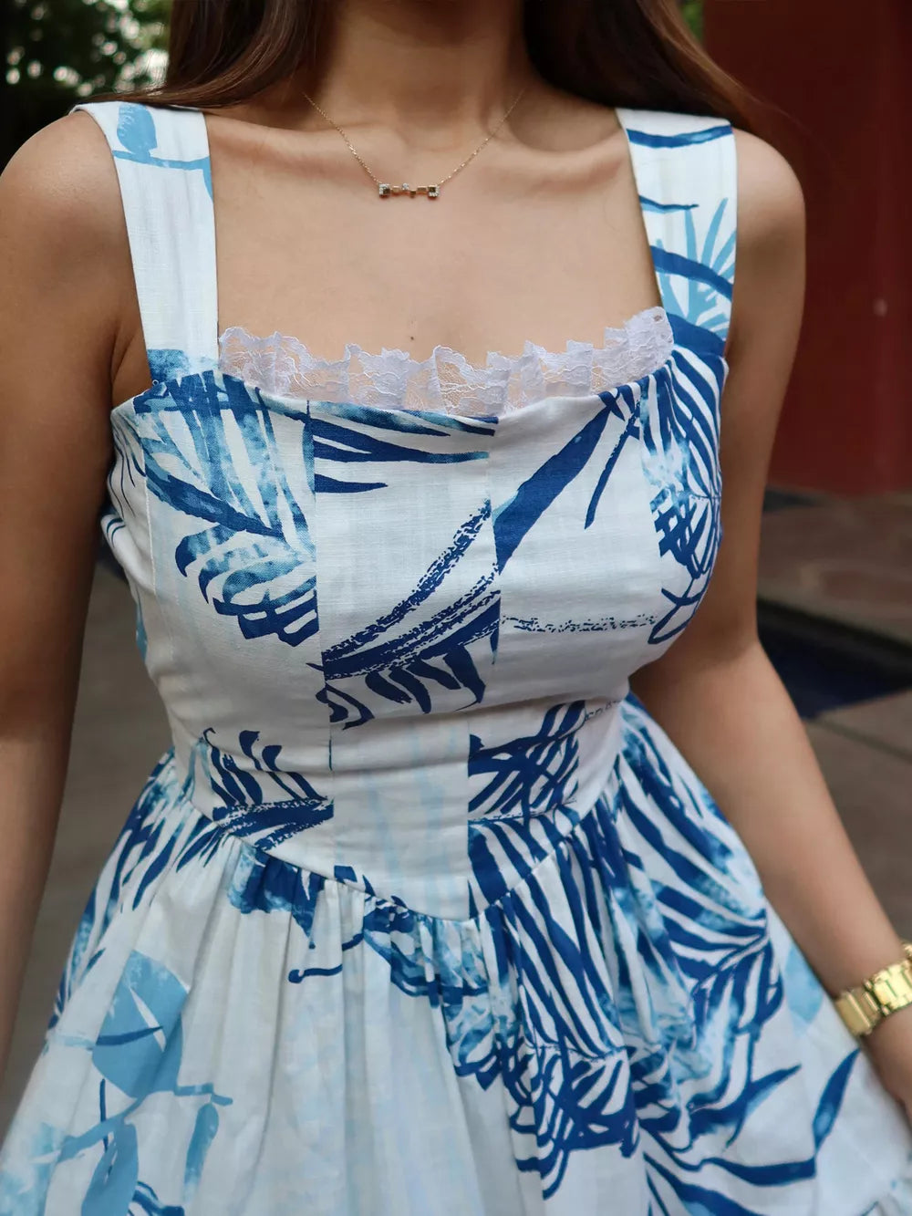 Lace-trimmed blue tropical leaf maxi dress with square neckline and wide straps.