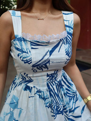 Lace-trimmed blue tropical leaf maxi dress with square neckline and wide straps.
