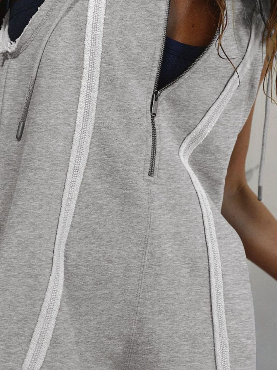 Gray sleeveless hooded romper with raw edge trim and zipper detail