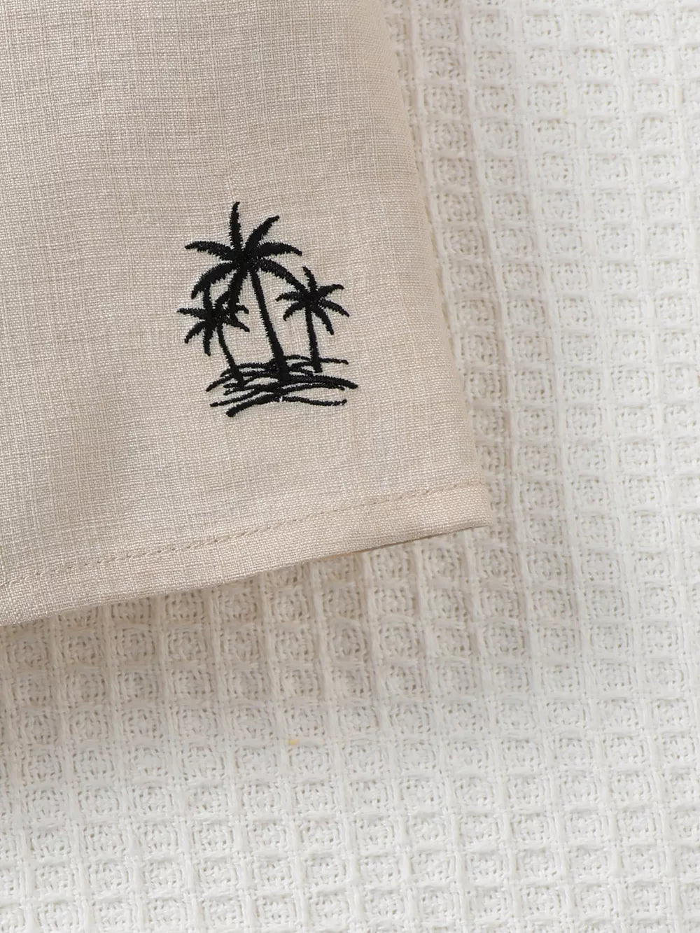 Two-piece kids' set in beige linen-look fabric with black embroidered palm trees.