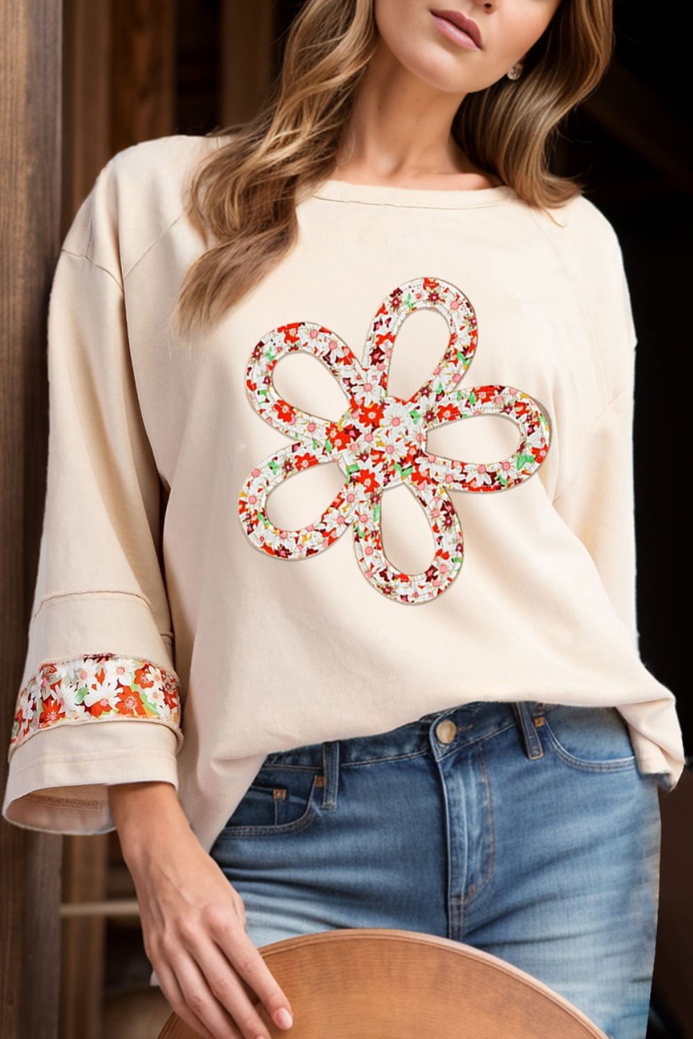 Ivory sweatshirt with floral appliqué and raglan sleeves, featuring floral trim on cuffs.