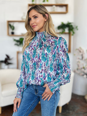 High neck abstract print blouse in red-violet and sky blue with smocked cuffs and collar.