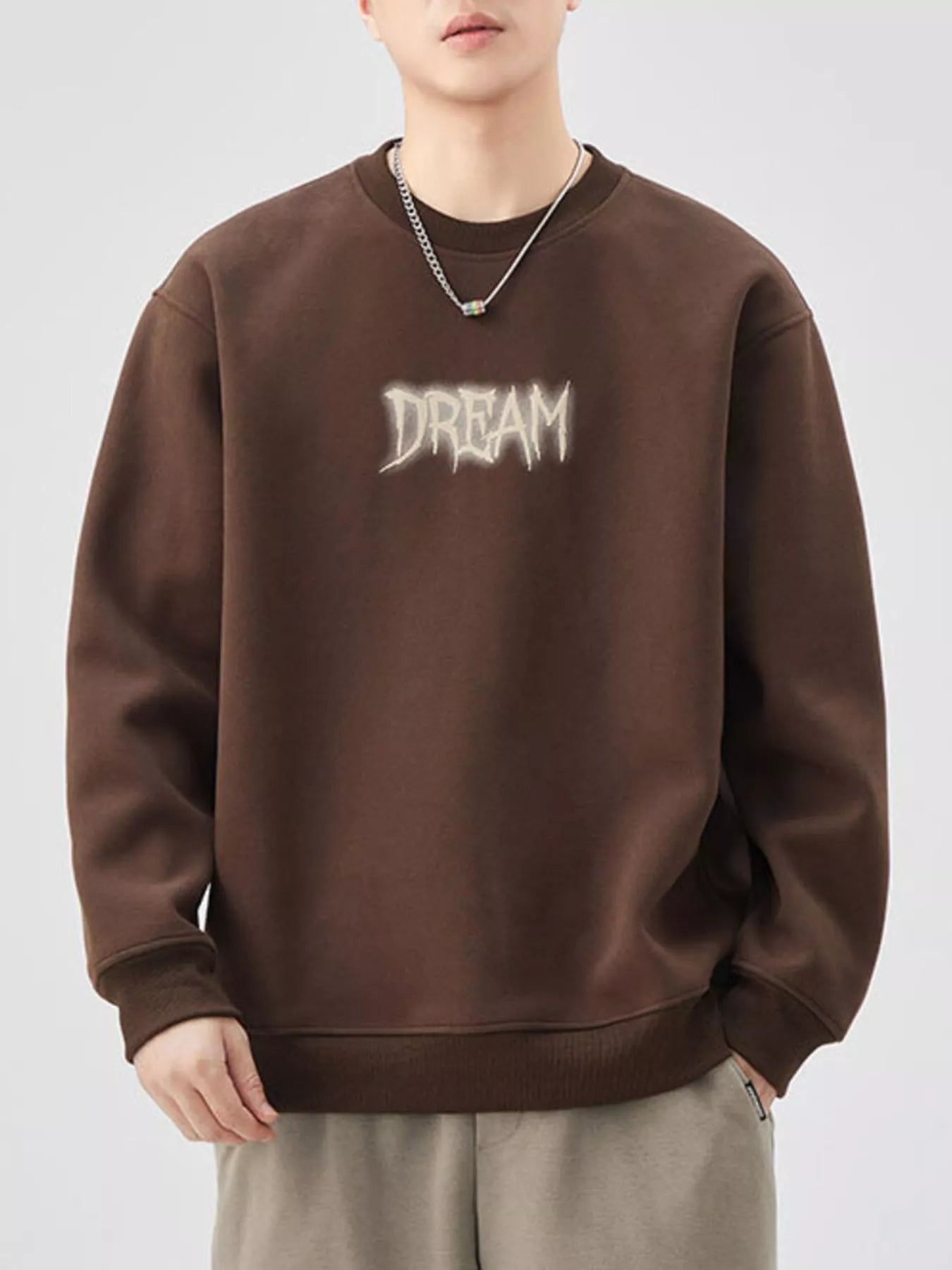 Brown crew-neck sweatshirt with "DREAM" graphic detail and ribbed cuffs and hem.