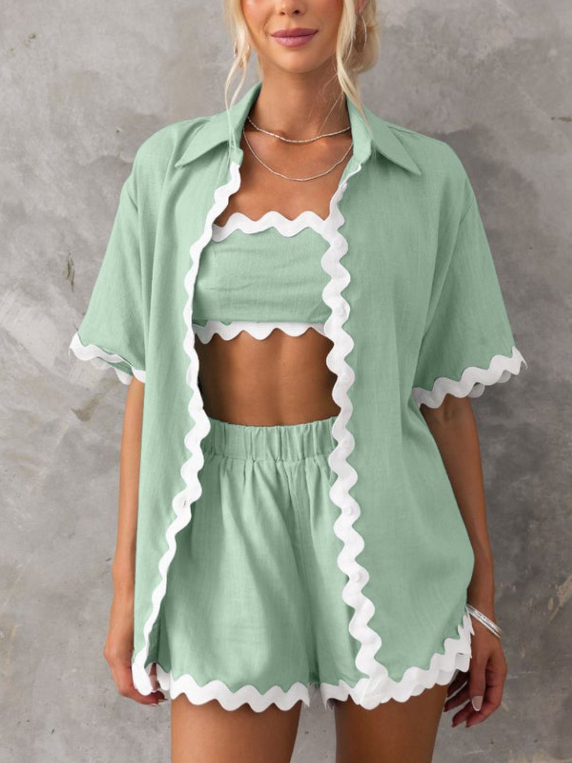 Scalloped edge linen shirt set in gum leaf green with white trim, featuring a button-down shirt, crop top, and shorts.