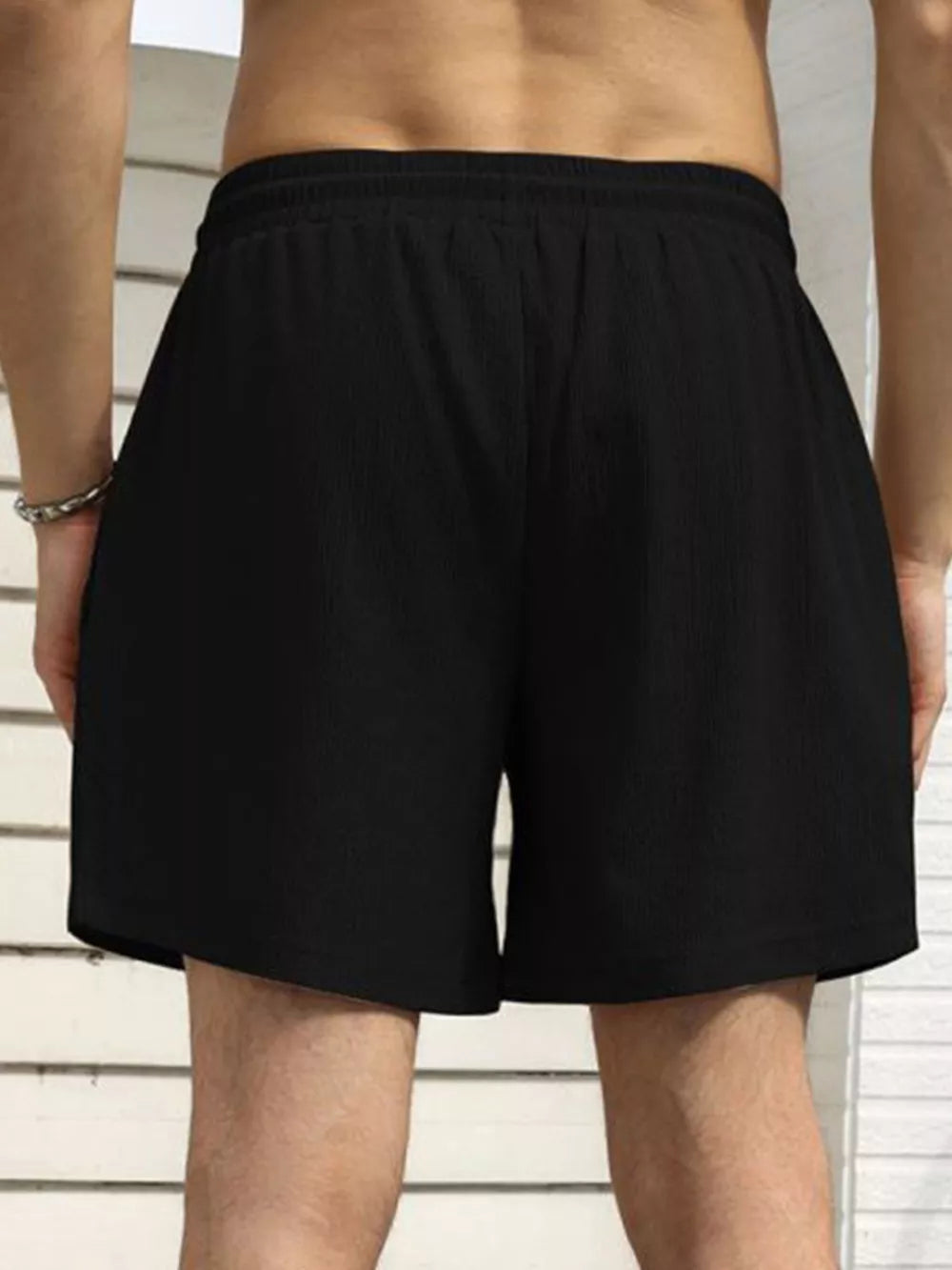 Men's black drawstring chino shorts with textured fabric and elastic waistband.